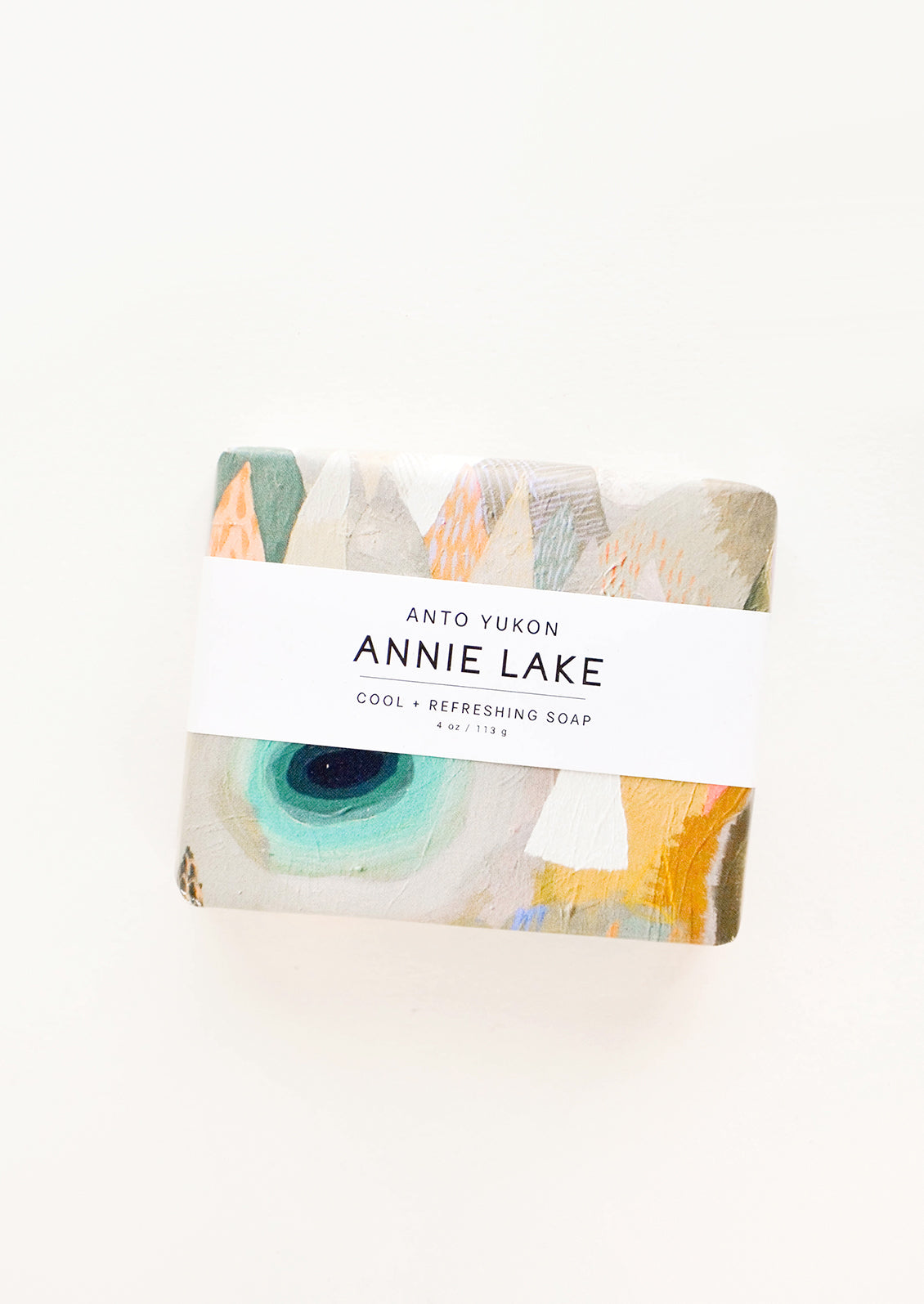 A bar of soap in multicolored packaging with a white horizontal label.