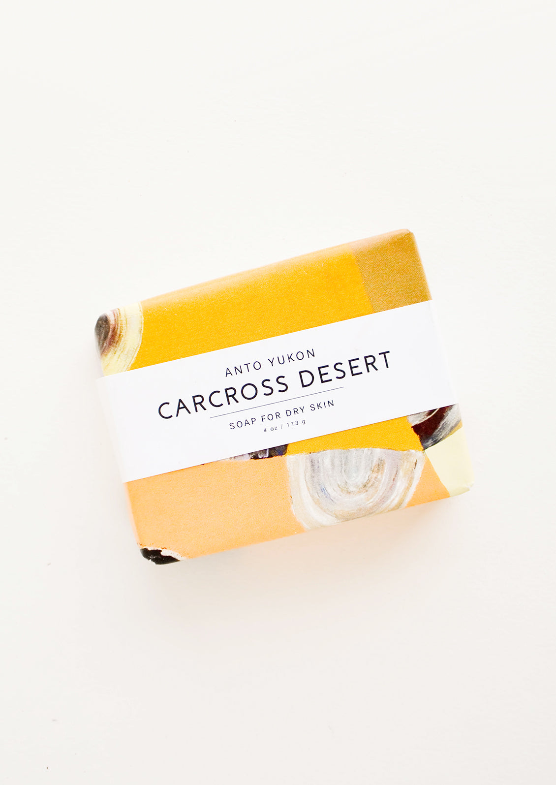 A bar of soap in patterned orange packaging with a white horizontal label. 