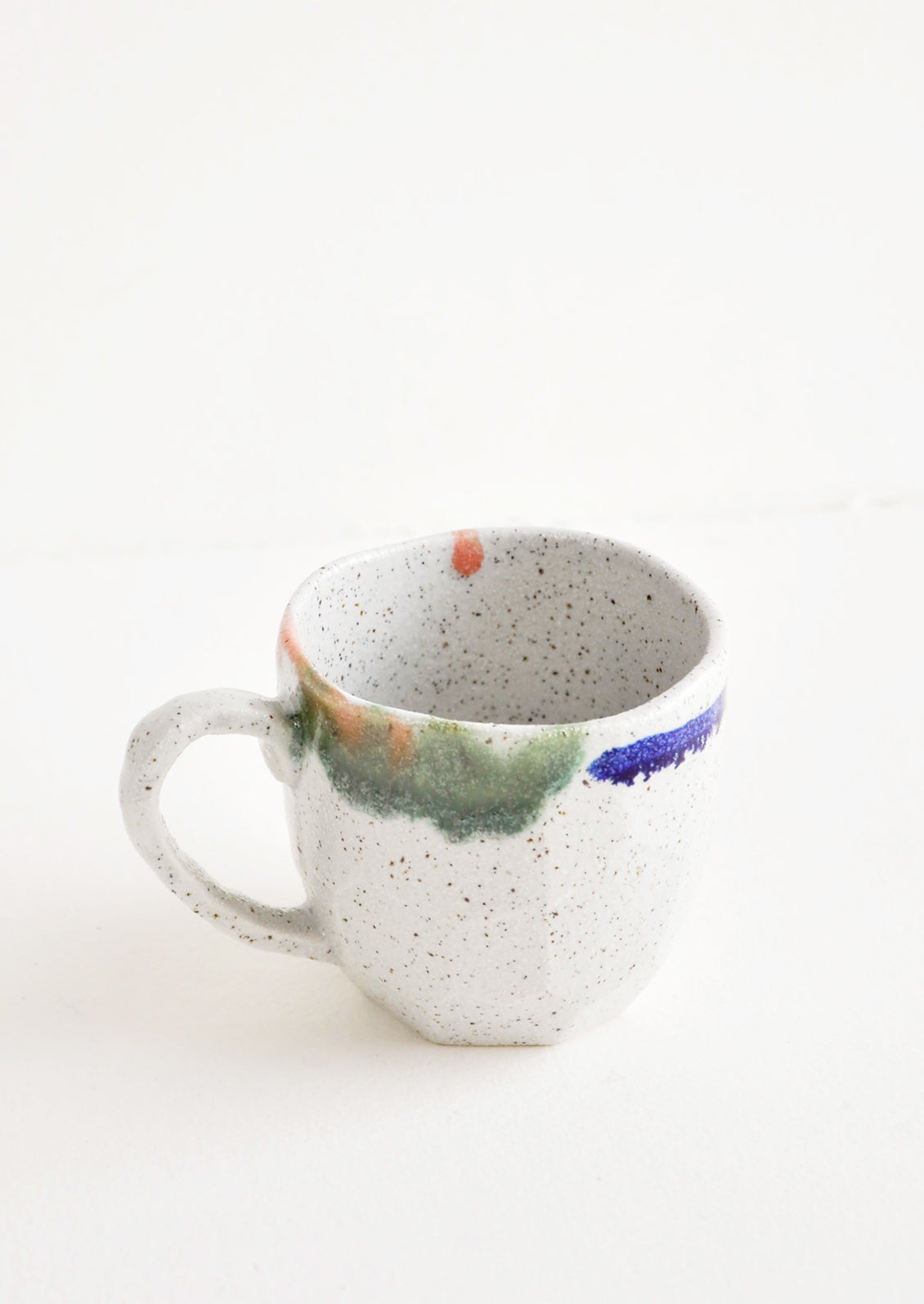 A short gray ceramic mug with blue, green, and pink painted rims.