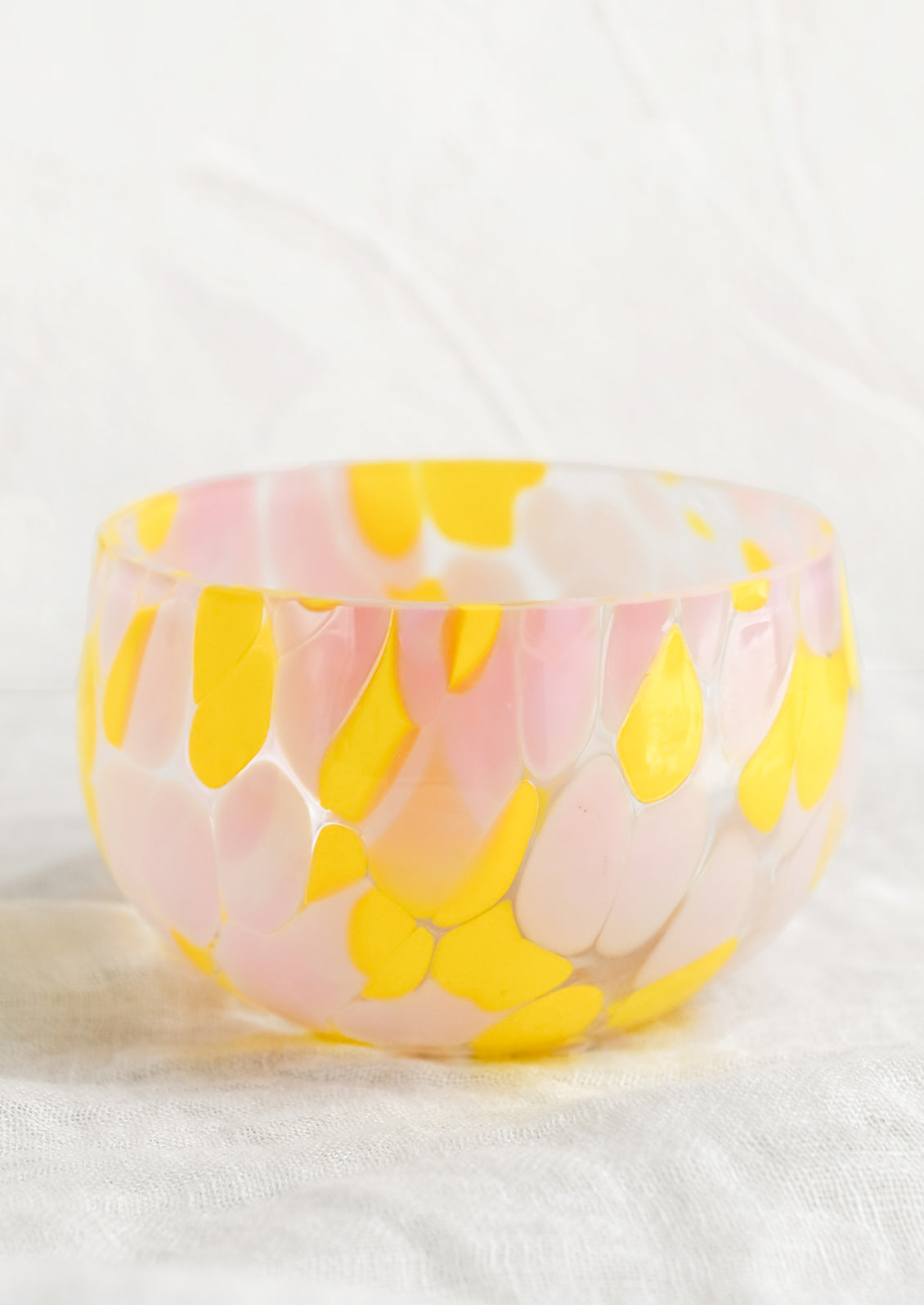 A speckled glass candy bowl in pink and yellow.