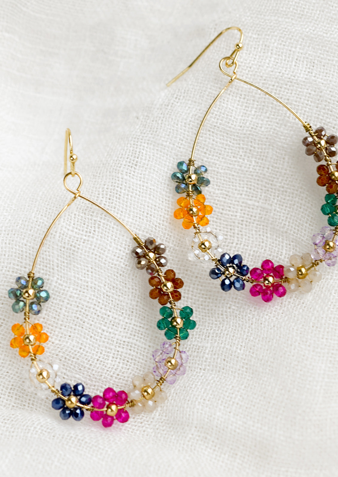 A pair of gold teardrop wire earrings with bright floral beading.