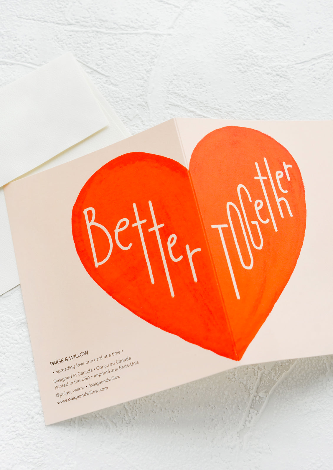 A greeting card with large red heart printed across card fold, reading "Better together".