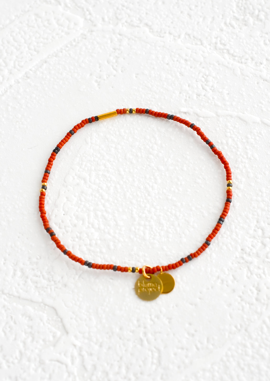 Seed bead bracelet in rust and navy with brass accents