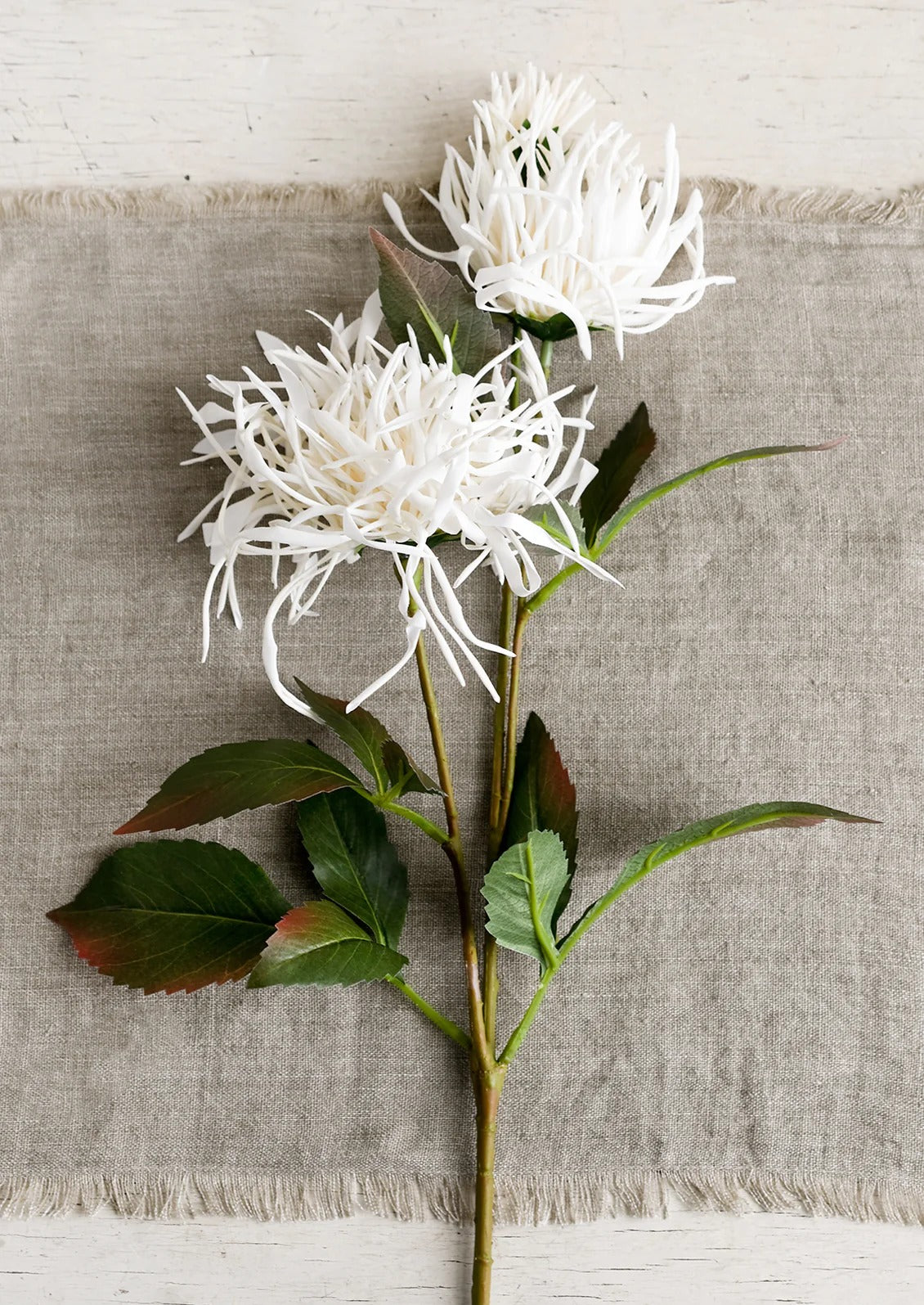 A greige table runner with white flower.