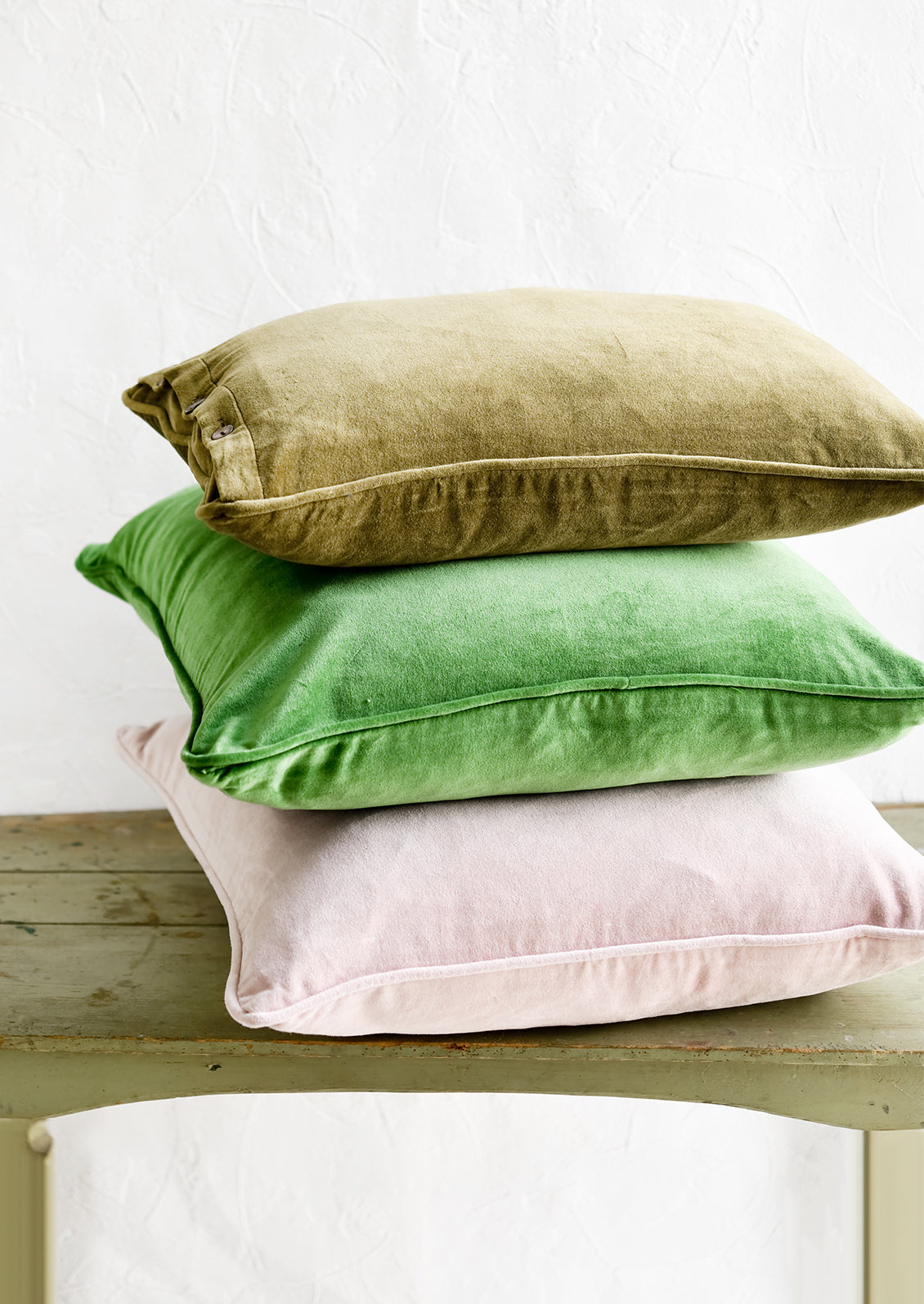 A stack of velvet pillows in green and pink.