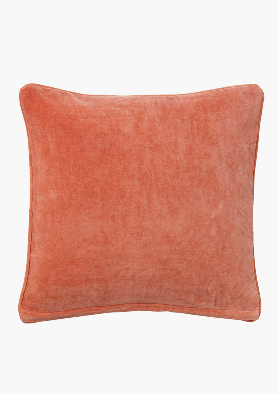 A square velvet throw pillow in coral red.