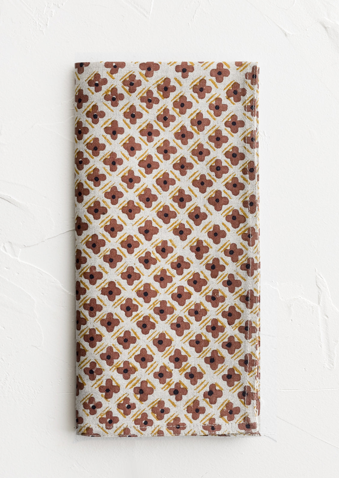 A block printed napkin with clay and yellow floral print.