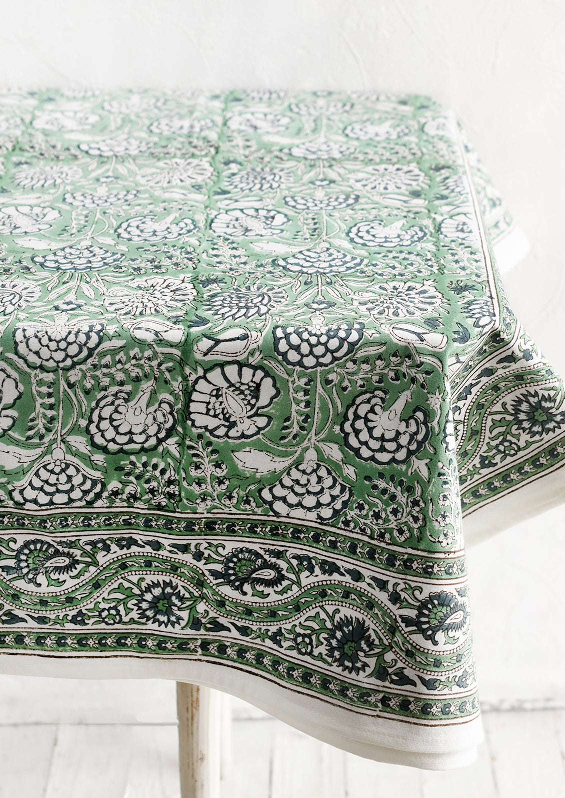 A block printed tablecloth with traditional print in blue and green shades.