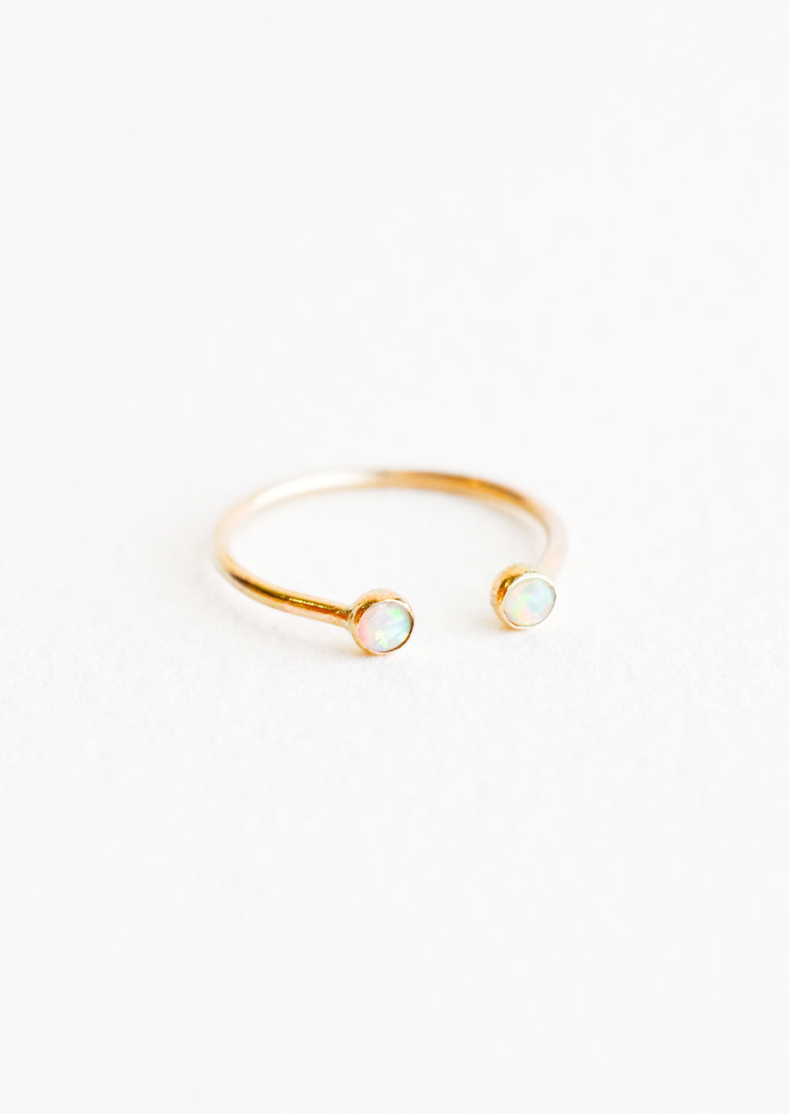 Yellow gold adjustable ring with opening at front and an opal stone on each side of the opening.