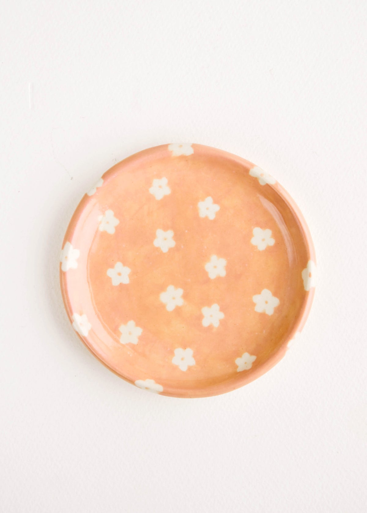 Small, round ceramic dish in peach with small white flowers