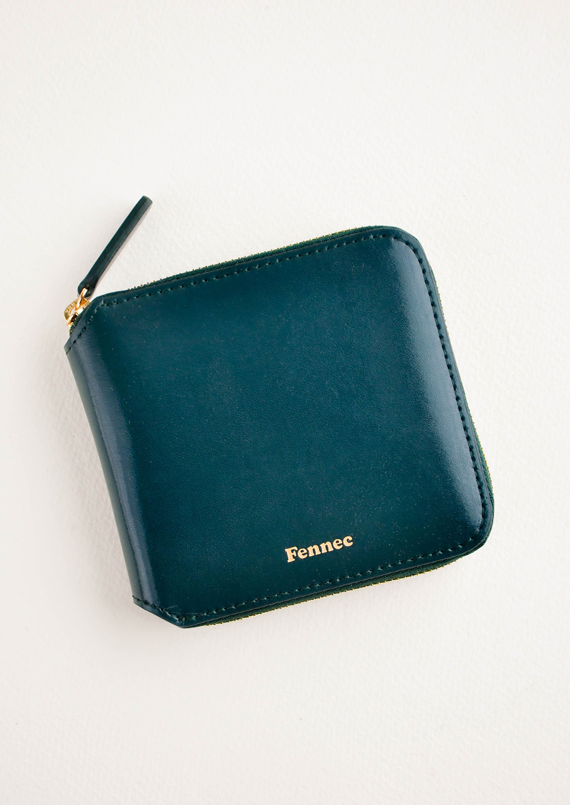 Dark green leather wallet that zips on three sides, with matching tab pull.