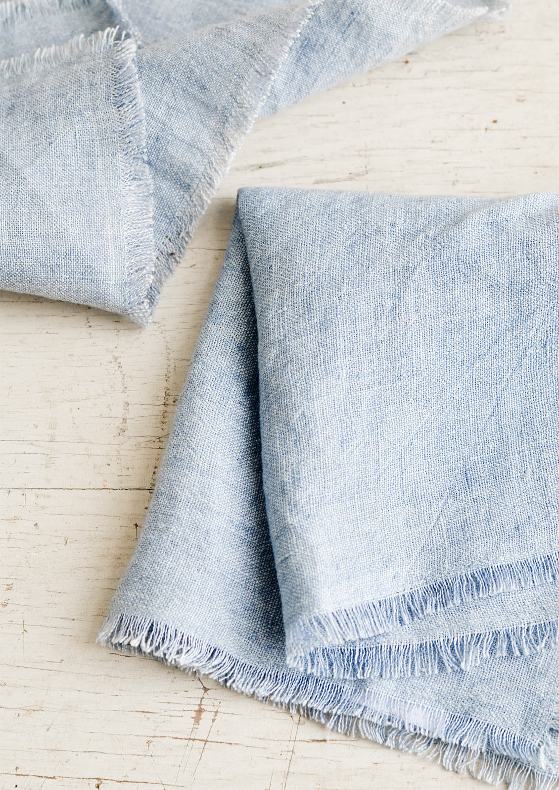 Folded blue linen napkins with frayed edges.