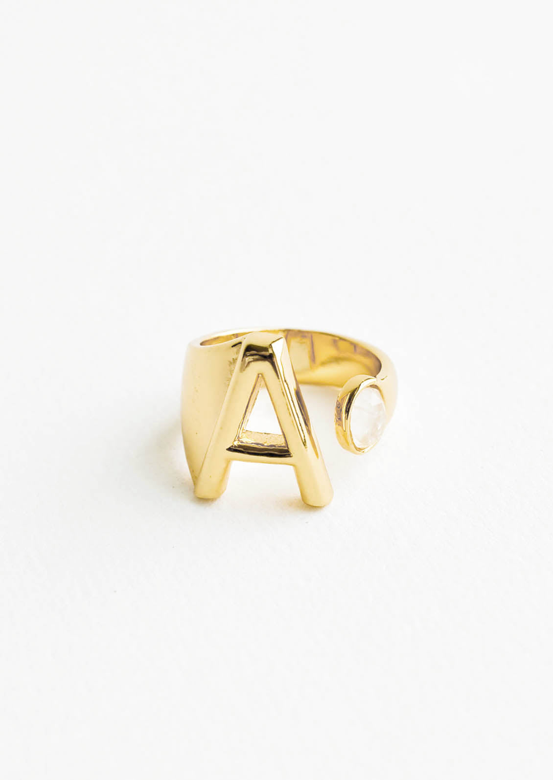 Yellow gold ring with letter A and oval glass crystal, and wide adjustable band.