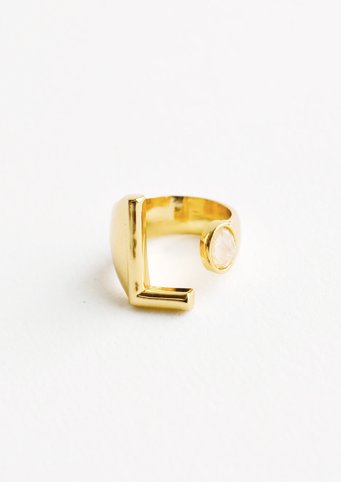 Yellow gold ring with letter L and oval glass crystal, and wide adjustable band.