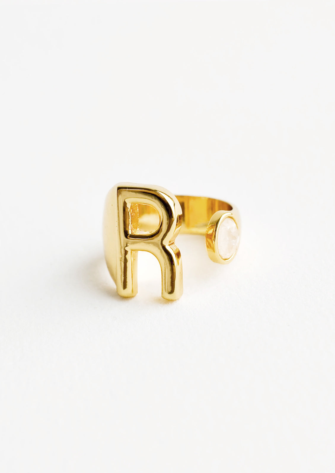 Yellow gold ring with letter R and oval glass crystal, and wide adjustable band.