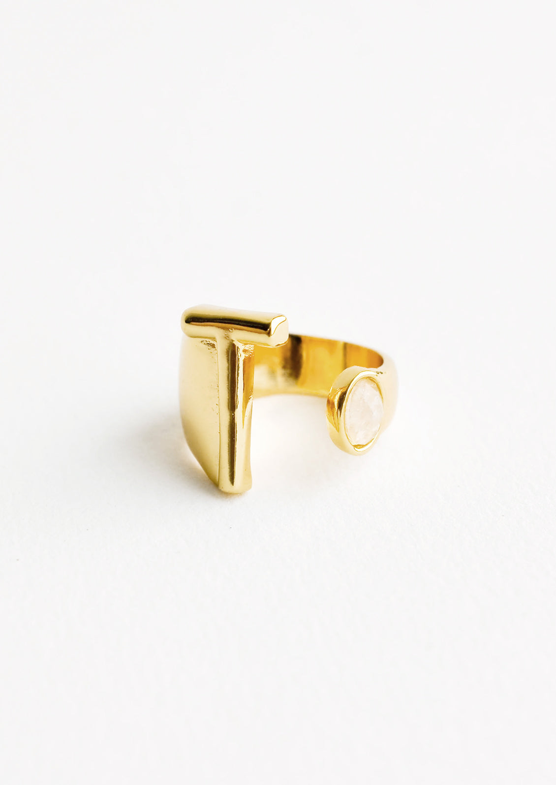 Yellow gold ring with letter T and oval glass crystal, and wide adjustable band.