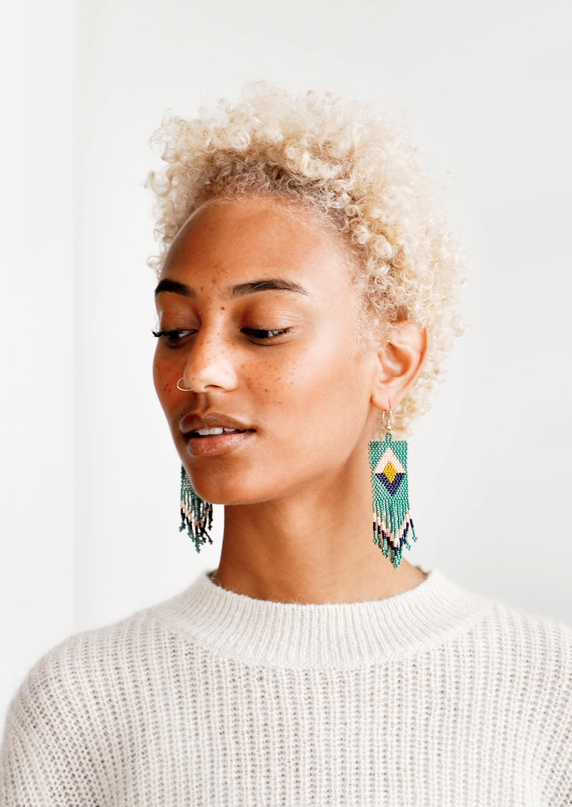 Model wears teal, pink, and navy fringe beaded earrings.