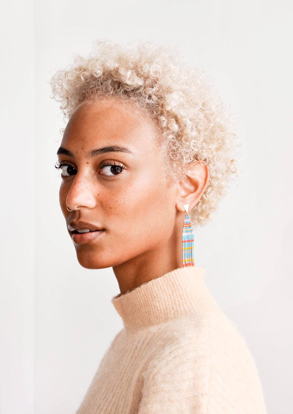 Model wears striped beaded fringe earrings.