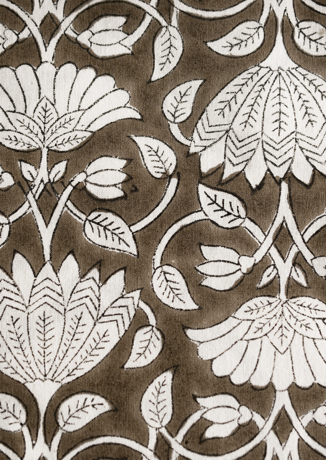 A block printed tablecloth with white lotus print on brown background.