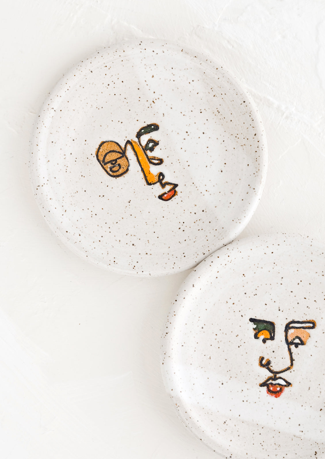 Two small speckled ceramic trinket dishes with and painted expressionist faces.