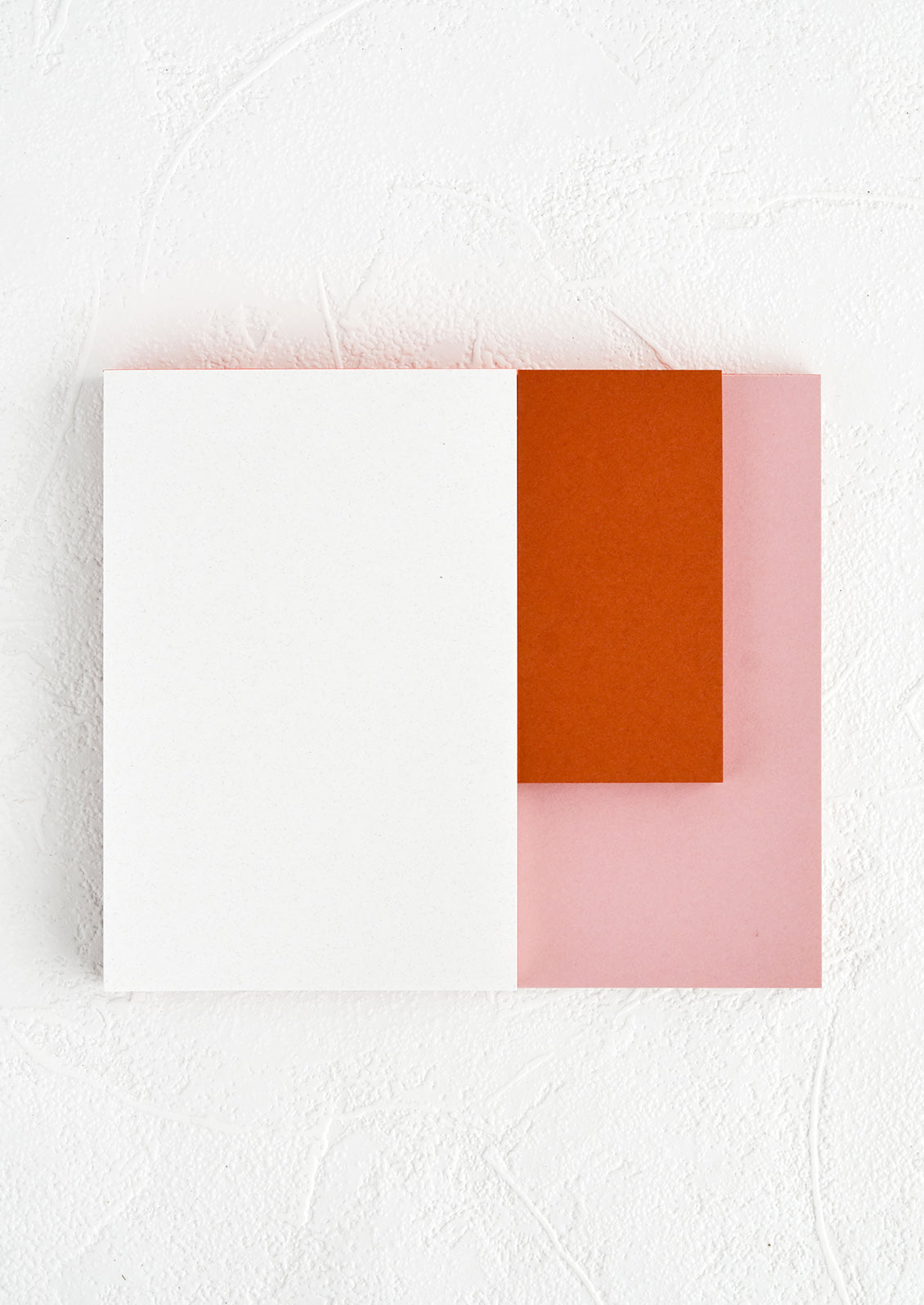 A landscape oriented notepad with three separate sized sections in different colors.