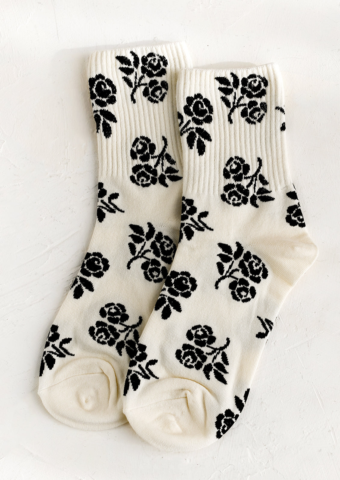 A pair of ivory socks with black floral print.