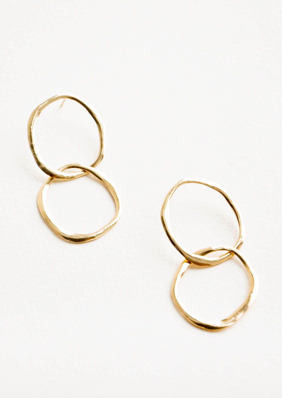 Gold drop earrings consisting of two interwoven hammered circles.