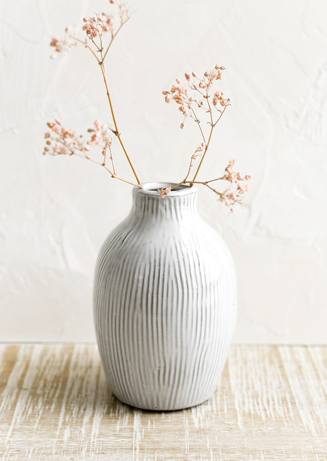A curvy ceramic vase in white with brown etched stripes.