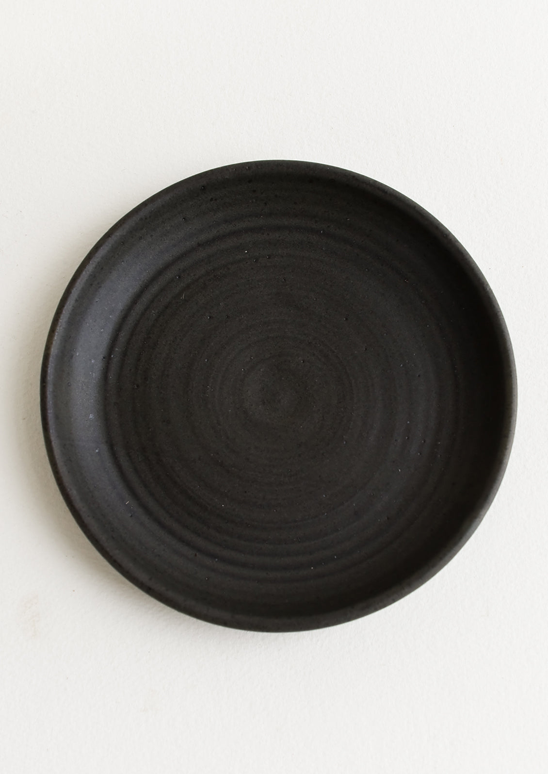 A ceramic side plate in a matte black glaze.
