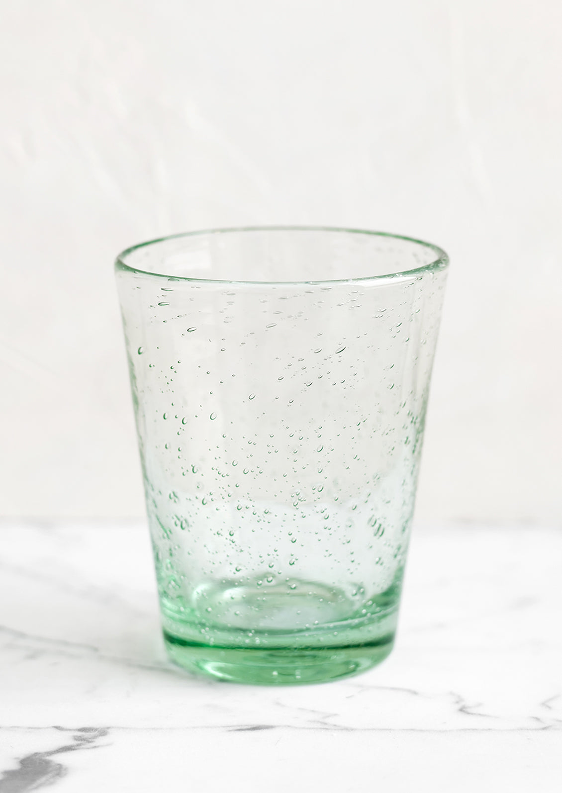 A glass tumbler cup in light green seeded glass.