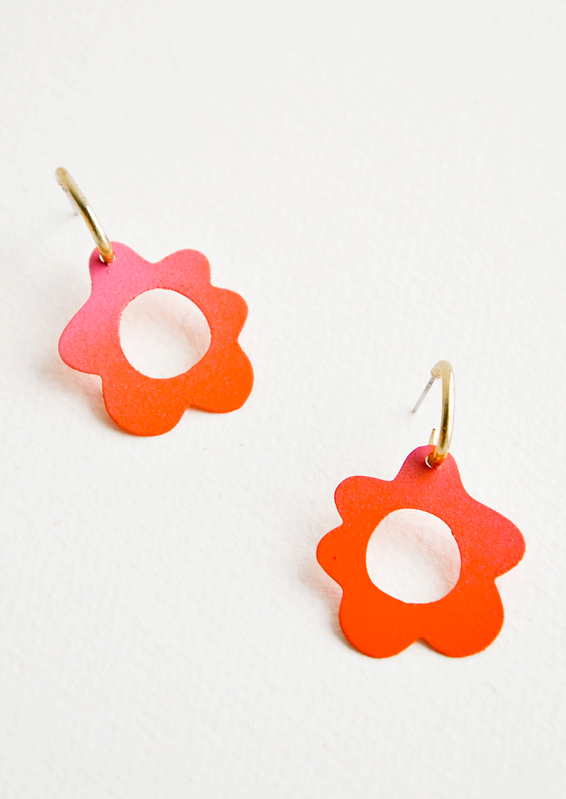 Coral flower shaped earrings with circular cutouts on small brass open hoops.