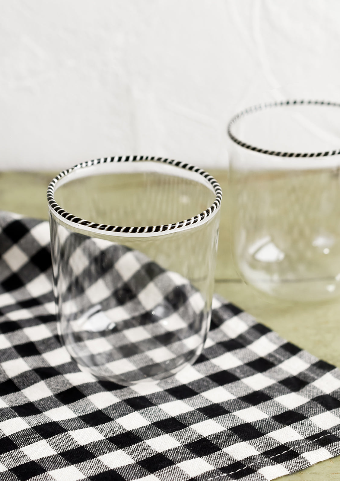 A pair of clear glass tumblers with black and white striped rim.
