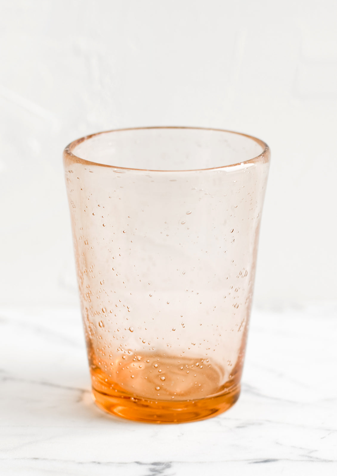 A glass tumbler cup in melon seeded glass.