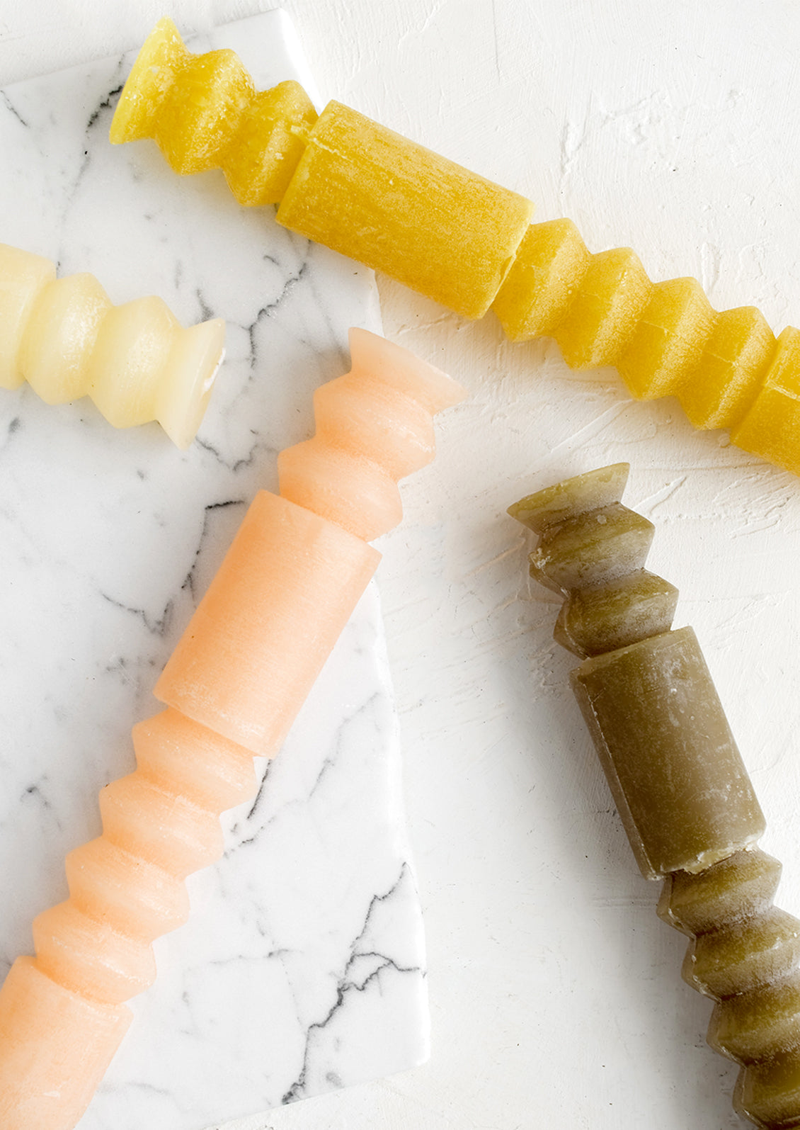 Carved geometric taper candles in assorted colors.