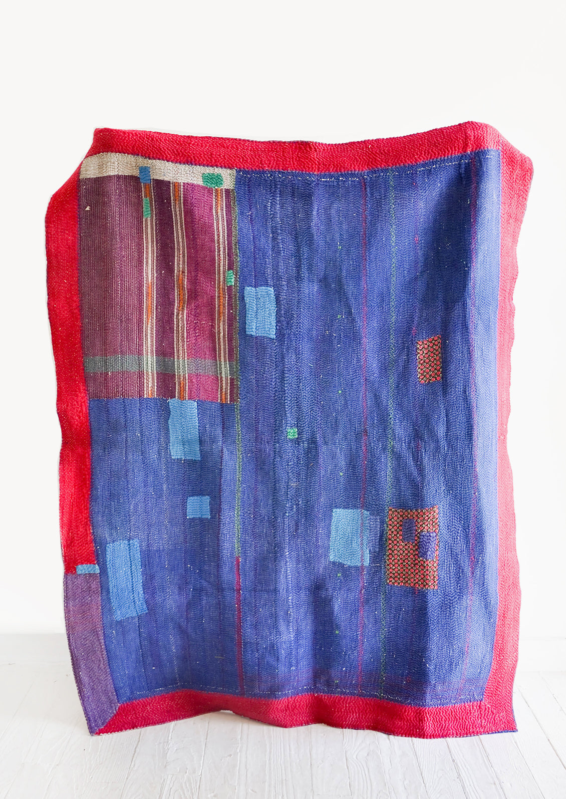 Vintage patchwork quilt in a mix of colors and fabrics. Predominantly dark blue with magenta accents.
