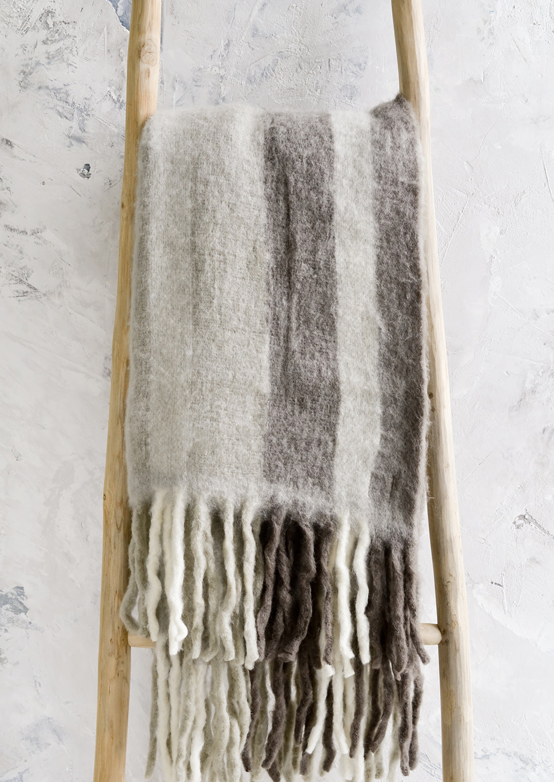A fuzzy throw blanket with exaggerated fringe in grey multi.