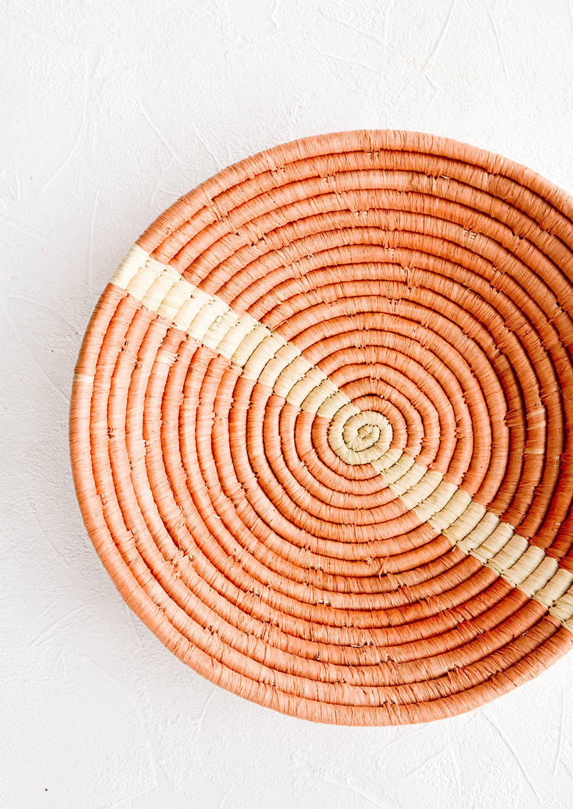Peach woven raffia bowl with natural streak across middle